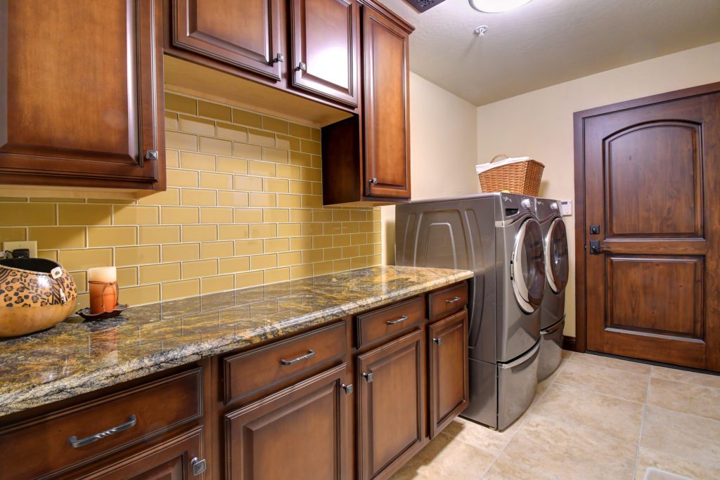A kitchen with brown cabinets and yellow tile.