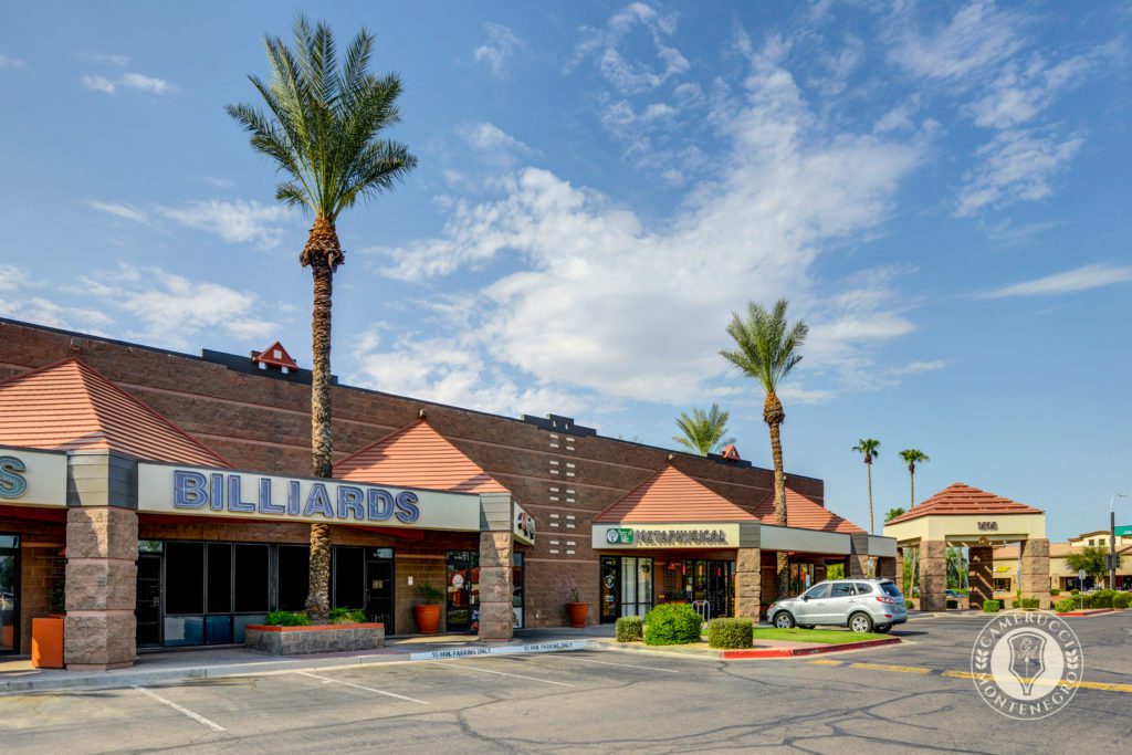 A parking lot with several buildings and palm trees.