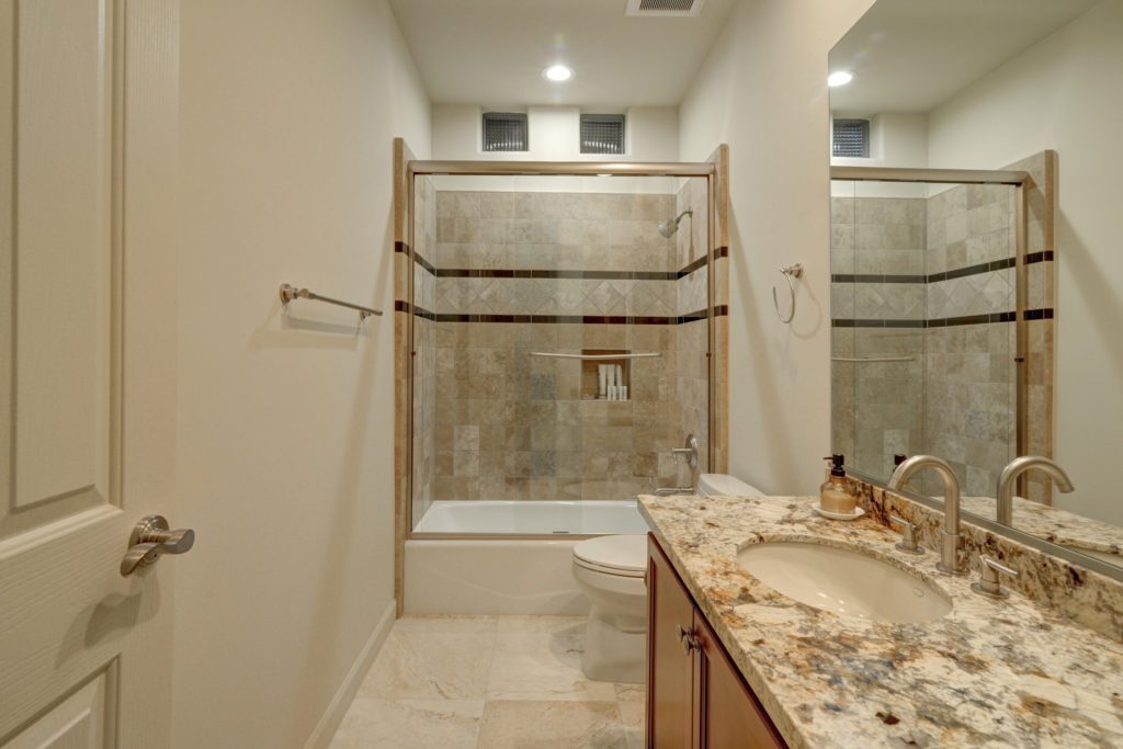 A bathroom with marble counter tops and beige tile.