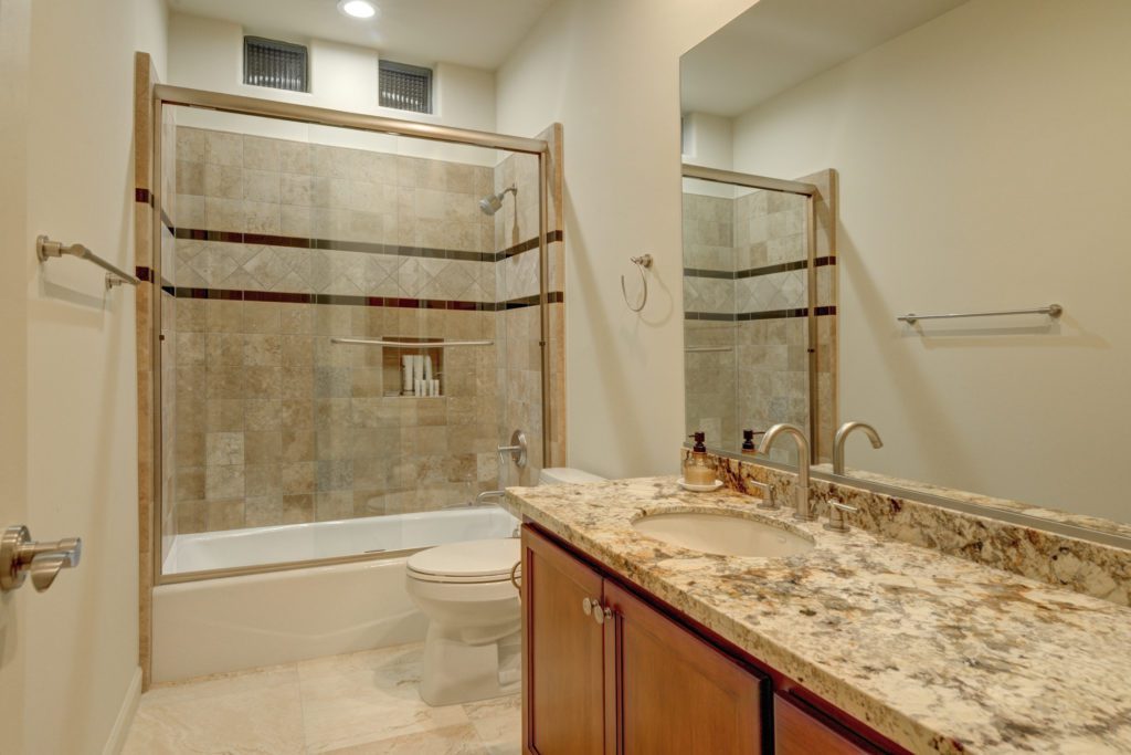 A bathroom with marble counter tops and tile walls.