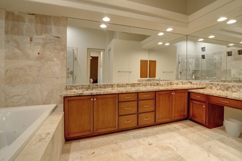A bathroom with a large mirror and wooden cabinets.