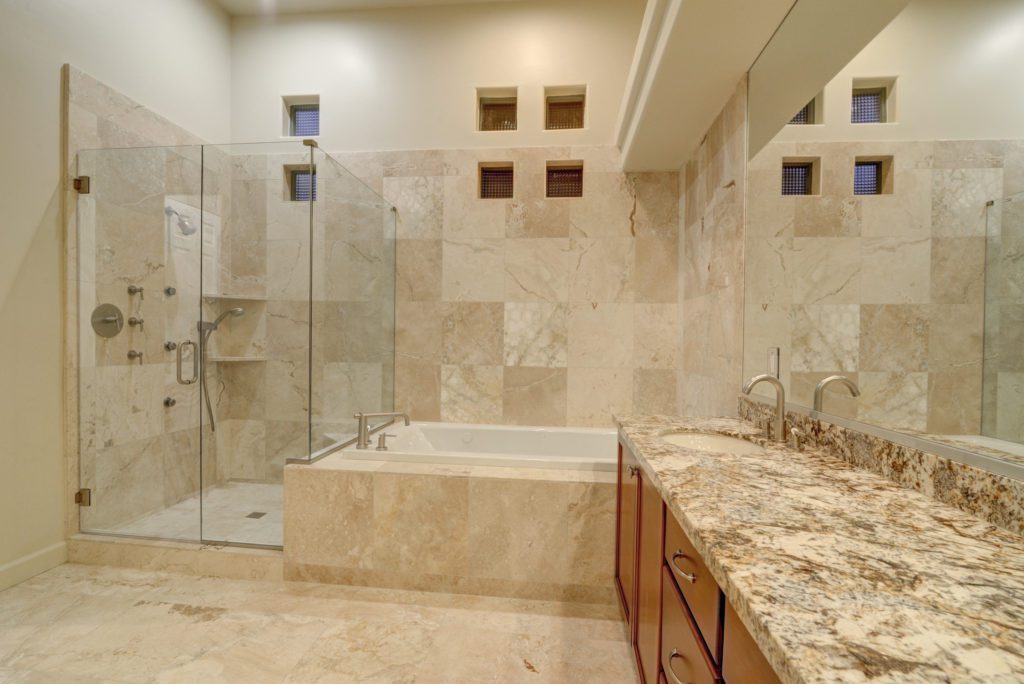 A bathroom with marble tile and a large shower.