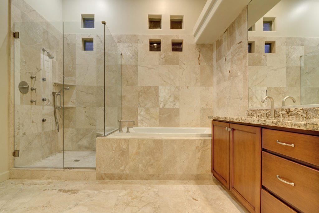 A bathroom with marble tile and wood cabinets.