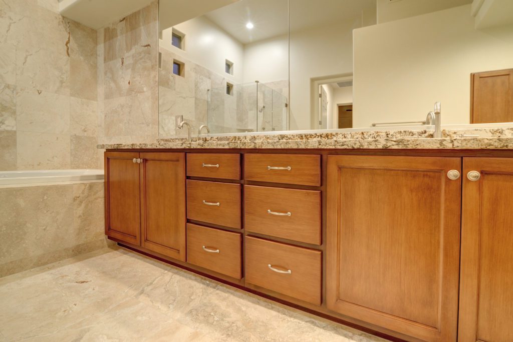 A bathroom with wooden cabinets and marble counter tops.