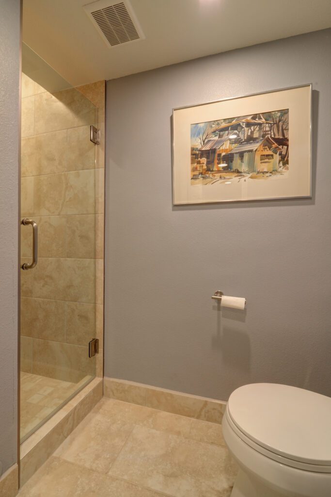 A bathroom with a shower, toilet and tiled floor.