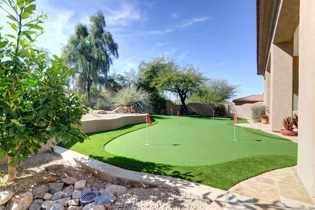 A backyard with a putting green and trees.