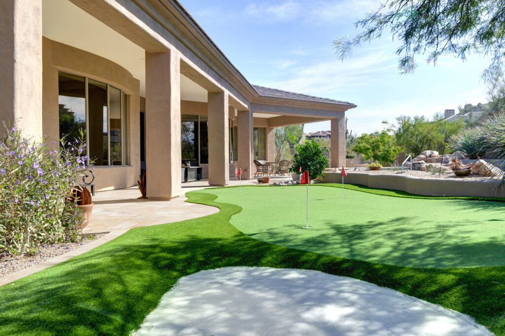 A large patio with grass and a golf hole.