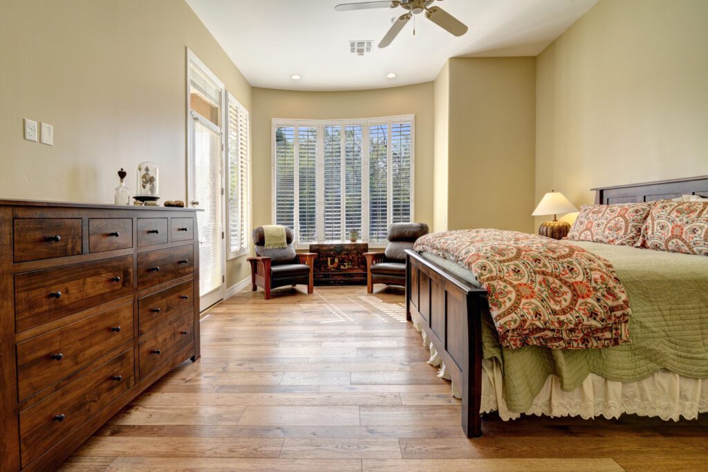 A bedroom with hardwood floors and a large window.