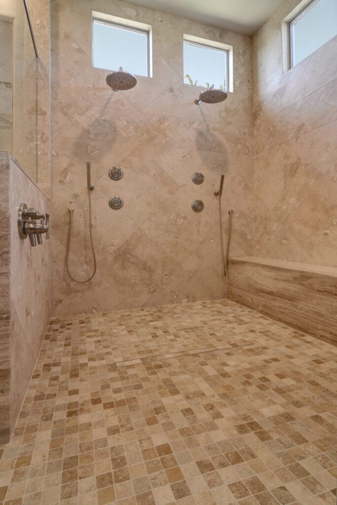 A bathroom with two shower heads and tiled walls.