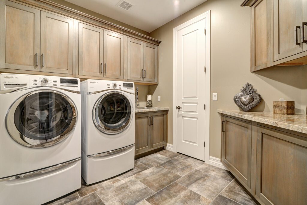 A laundry room with two machines and cabinets.