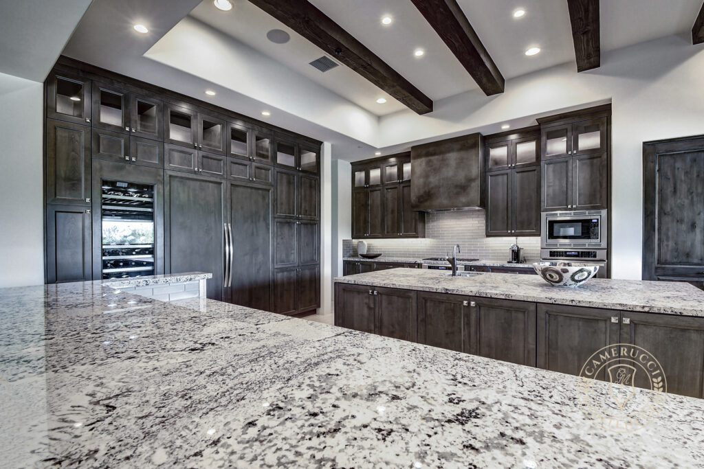 A kitchen with granite counter tops and dark cabinets.