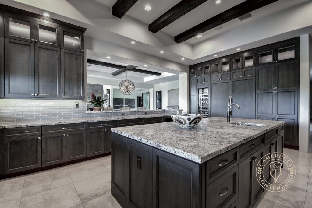 A large kitchen with black cabinets and white counter tops.