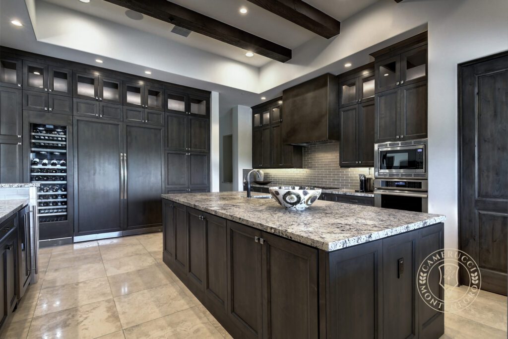 A kitchen with dark cabinets and white counters.