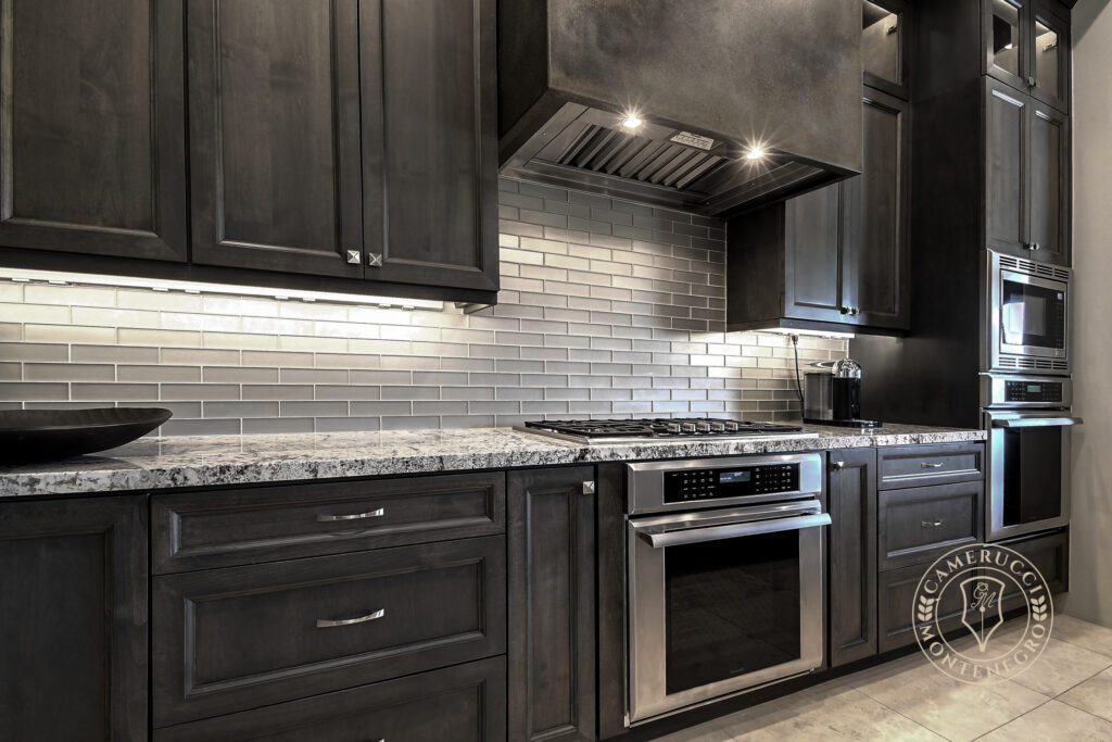 A kitchen with dark cabinets and white tile backsplash.