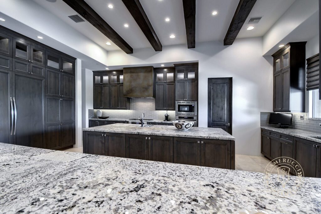 A large kitchen with granite counter tops and dark cabinets.