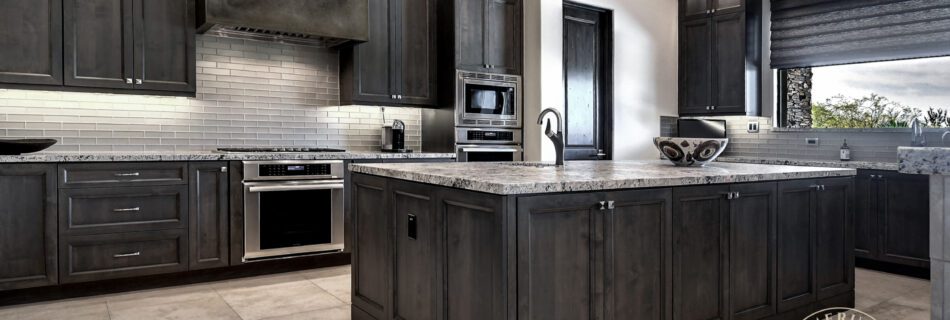A kitchen with dark cabinets and white counters