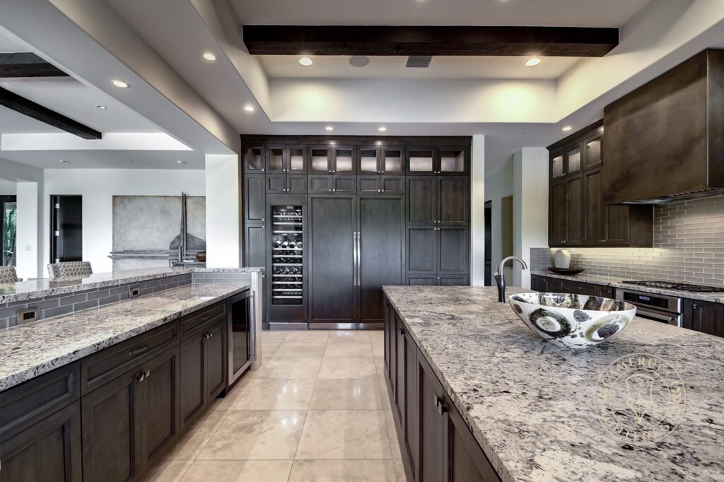 A large kitchen with granite counters and dark cabinets.