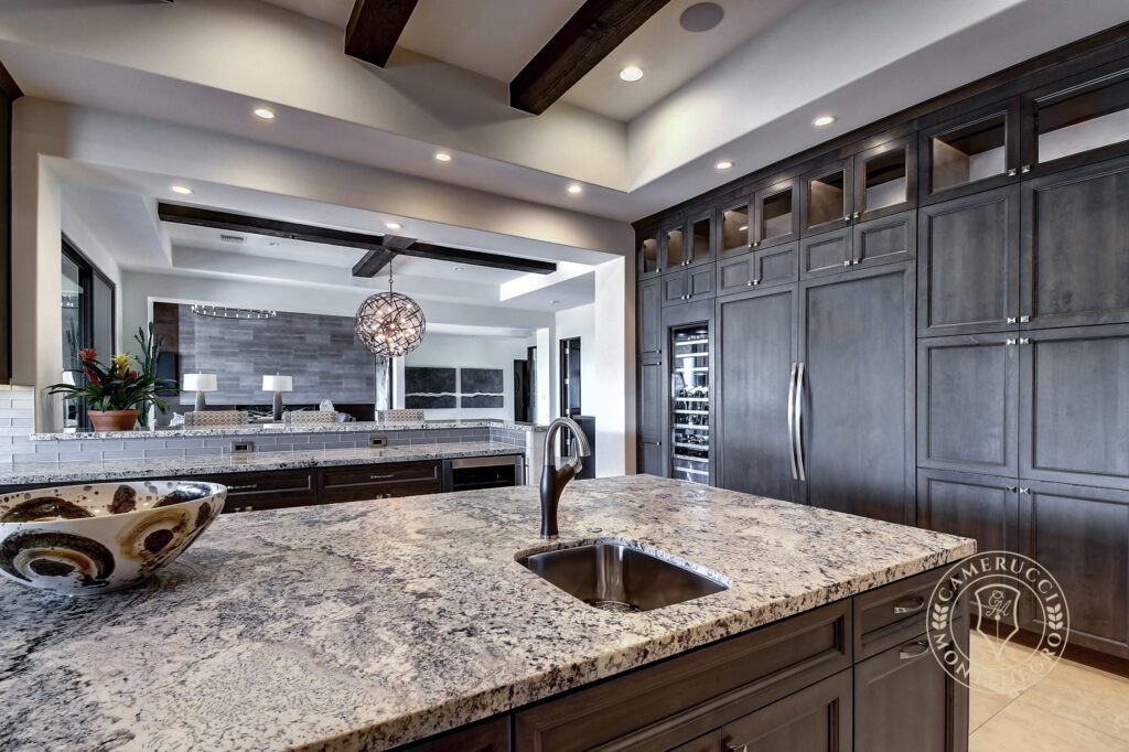A kitchen with granite counter tops and dark wood cabinets.
