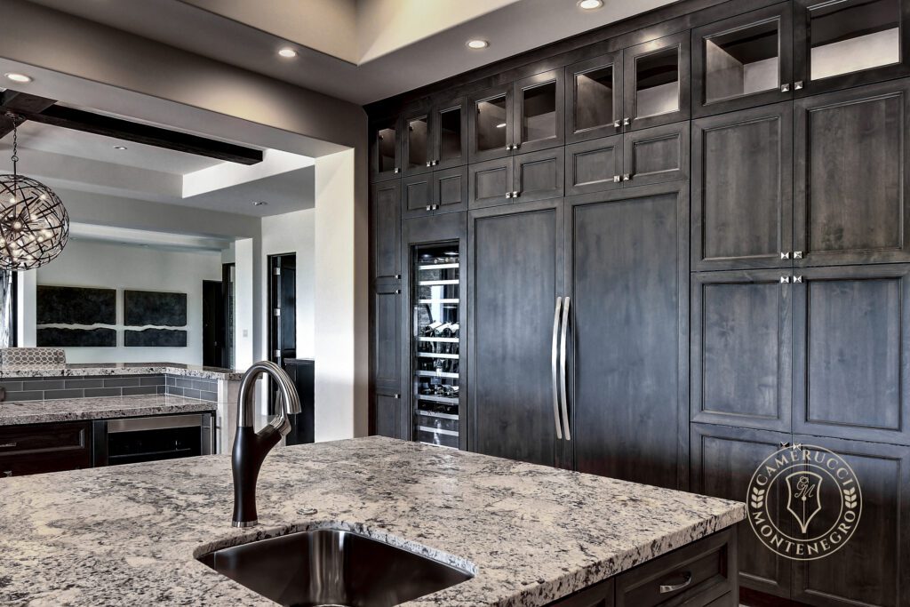 A kitchen with granite counter tops and black cabinets.