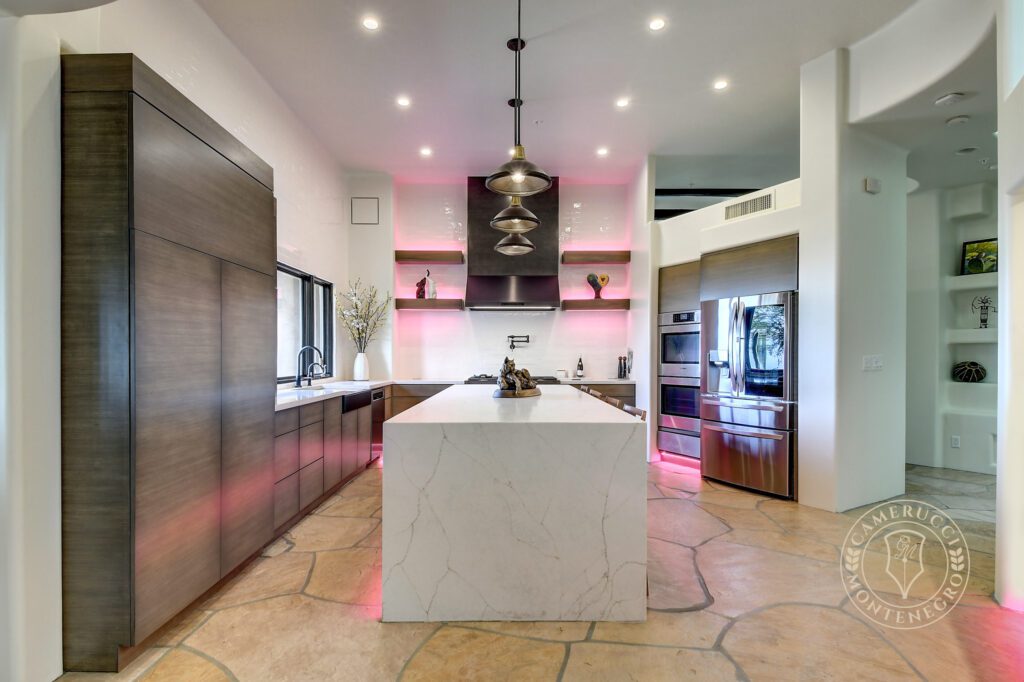 A kitchen with a large island and a pink light.