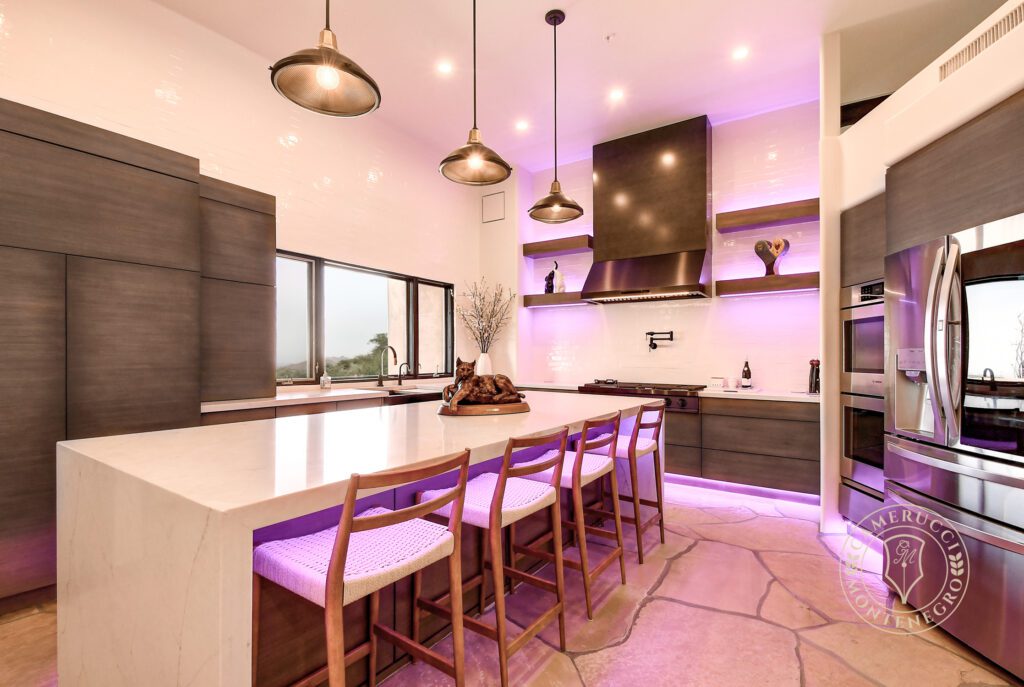 A kitchen with a large island and purple lighting.