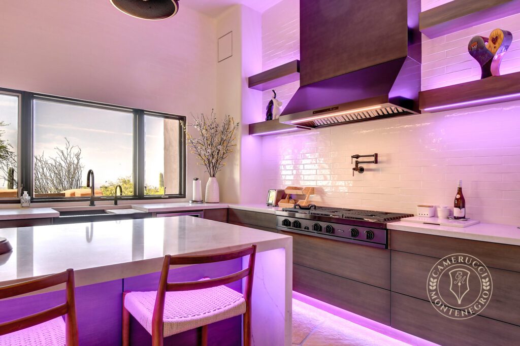 A kitchen with purple lighting and white cabinets.