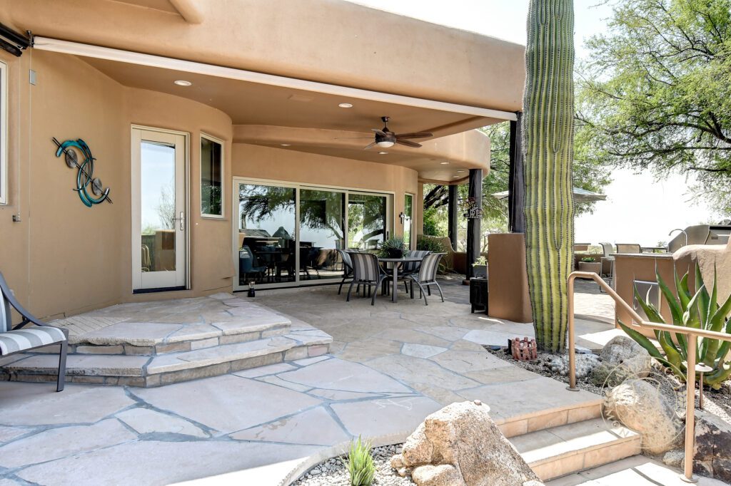 A patio with a table and chairs, a cactus and a fire pit.