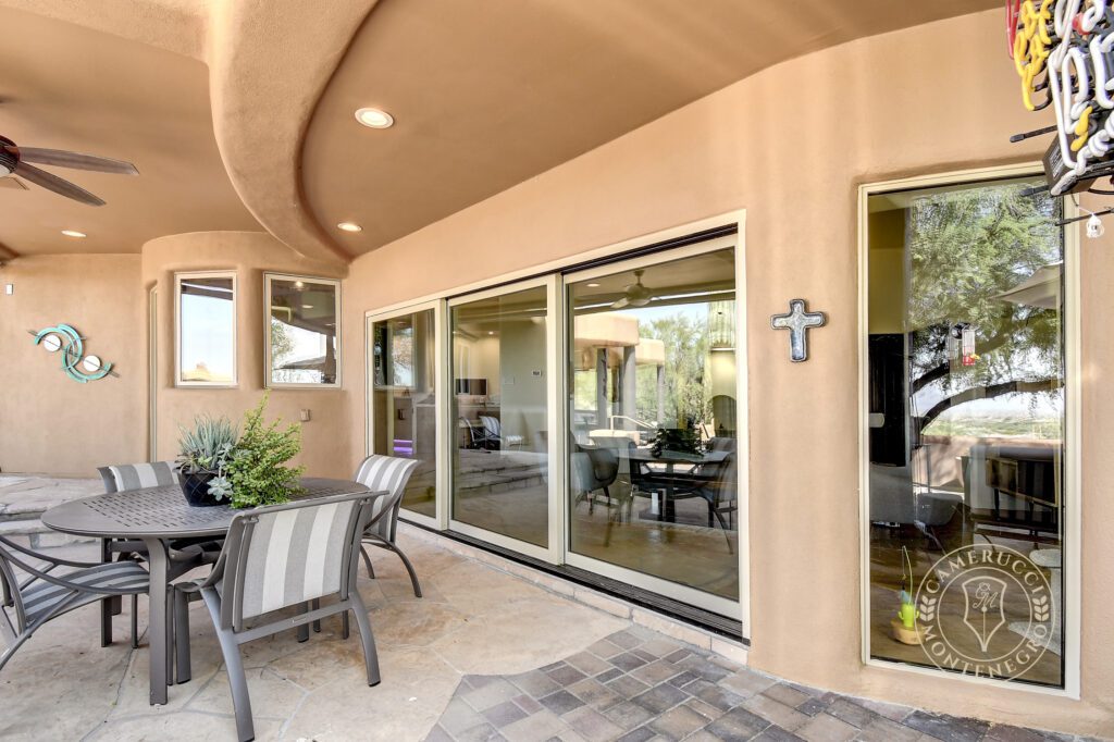 A patio with chairs and tables outside of it