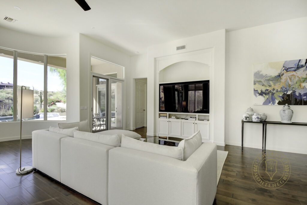 A living room with white furniture and a flat screen tv.